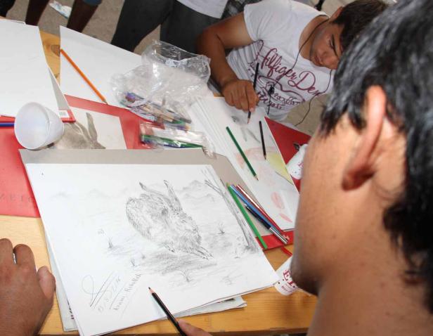 Ein junger Mann zeichnet einen Hasen auf Papier.