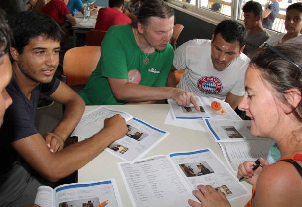 Eine Gruppe von Leuten sitzt an einem Tisch und schaut in Bücher.