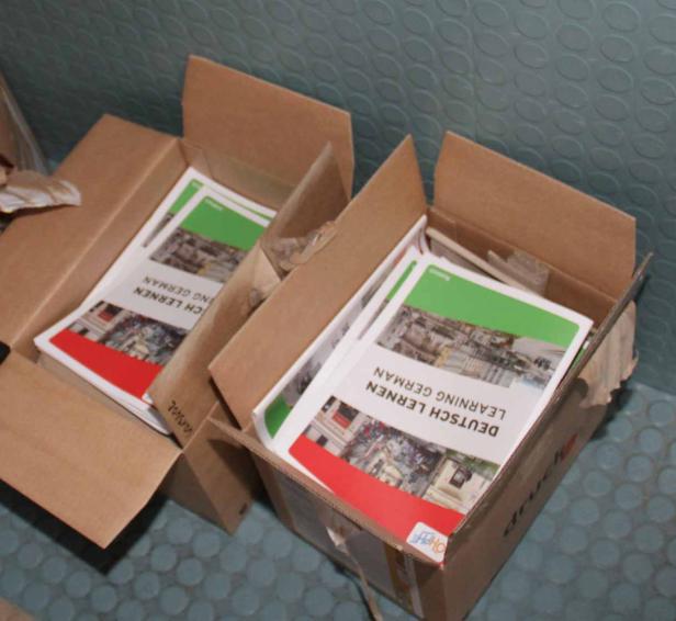 Zwei offene Kartons enthalten Bücher zum Deutschlernen.