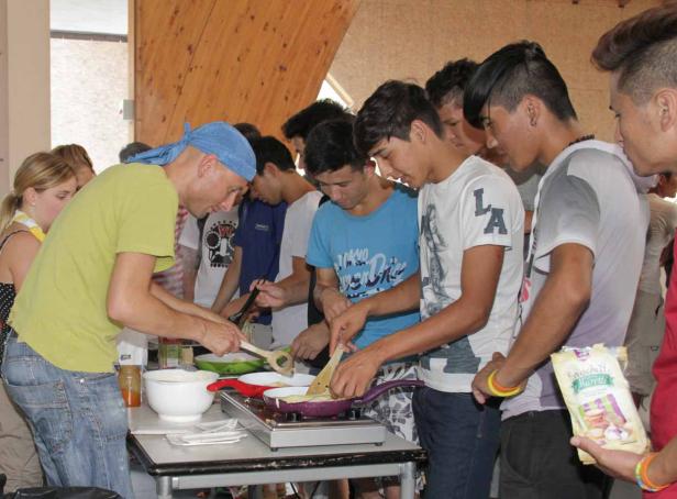 Eine Gruppe junger Leute steht an einem Tisch und bereitet Crêpes zu.