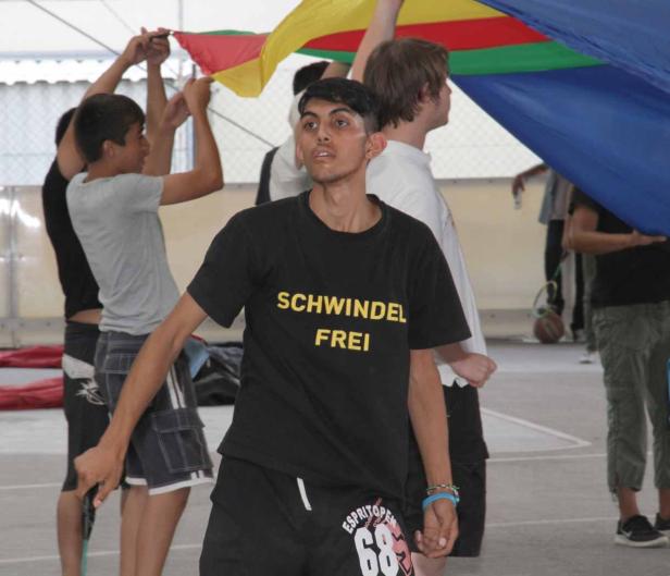 Eine Gruppe junger Leute hält einen bunten Schwungtuch hoch.