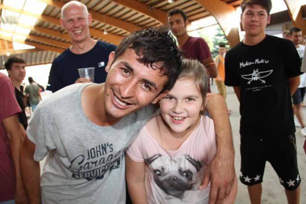 Ein Mann umarmt ein junges Mädchen, beide lächeln in die Kamera.