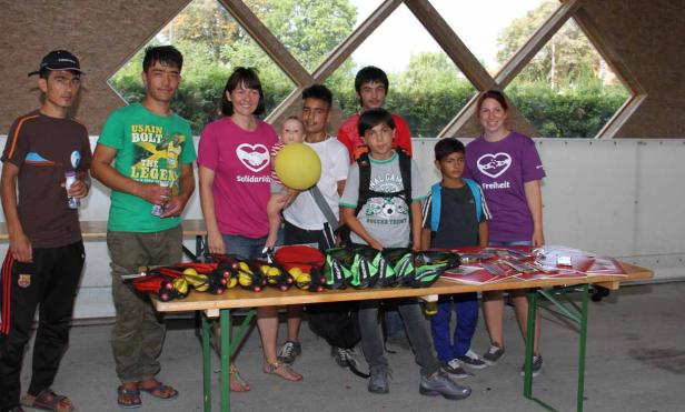 Eine Gruppe von Menschen steht an einem Tisch mit Sportartikeln.