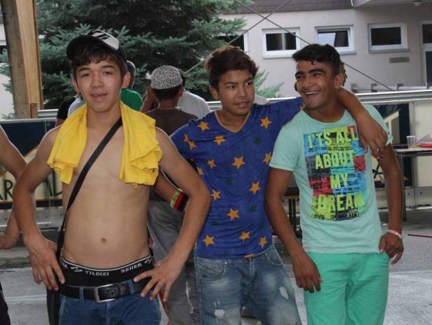 Drei junge Männer posieren lächelnd für ein Foto.