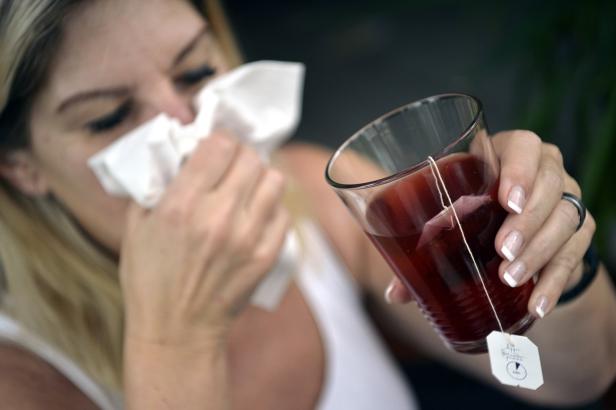 Themenbild Grippewelle 2022, Frau putzt sich die Nase