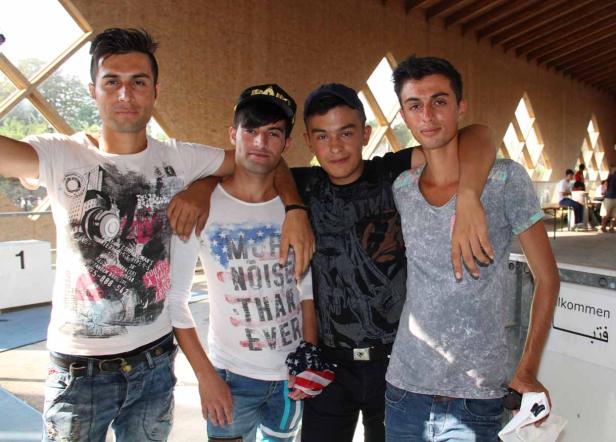 Vier junge Männer posieren mit verschränkten Armen für ein Foto.