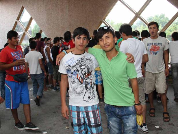 Zwei junge Männer stehen inmitten einer Menschenmenge und posieren für ein Foto.