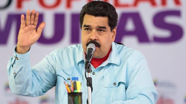Nicolás Maduro spricht bei einer Veranstaltung in ein Mikrofon und hebt die Hand.
