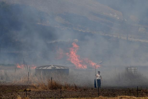 A resident fights a grass fire in the Hillville area near Taree