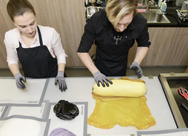 Zwei Personen formen Zuckerbonbons auf einer Arbeitsfläche.