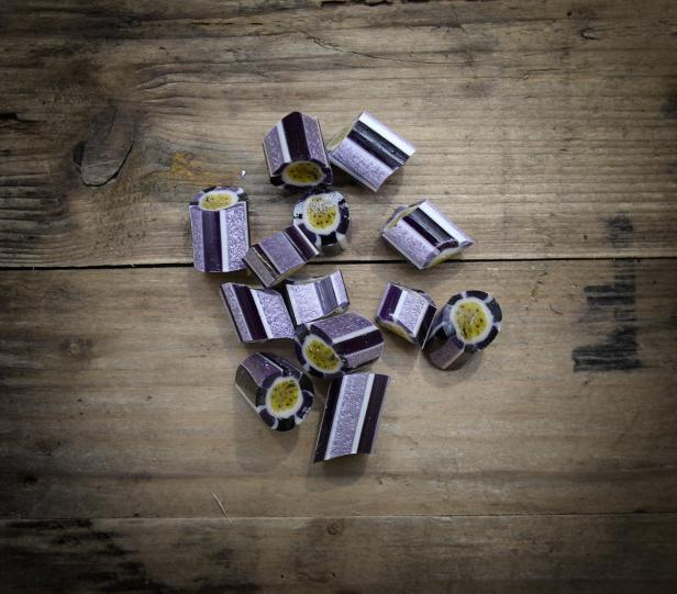 Mehrere Bonbons mit Passionsfruchtgeschmack liegen auf einem Holztisch.