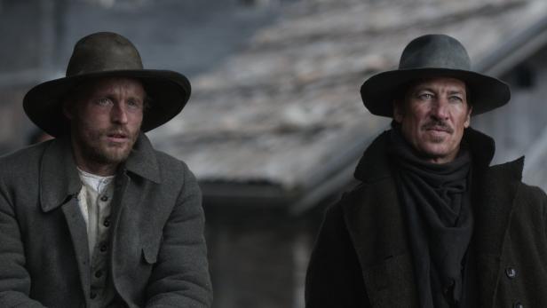 Zwei Männer mit Hüten und Mänteln, möglicherweise im Wilden Westen.