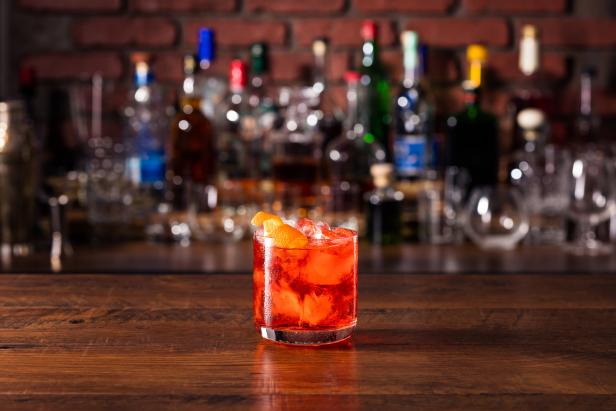 Ein Negroni-Cocktail mit Orangenschale auf einer Bar.