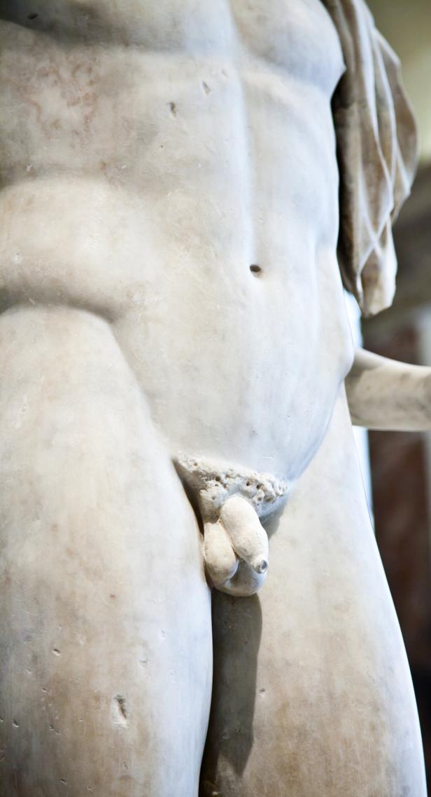 Detailaufnahme einer männlichen Marmorstatue von der Hüfte abwärts.