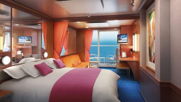 Ein Kabinenraum mit einem Bett, einem Sofa und einem Balkon mit Meerblick.