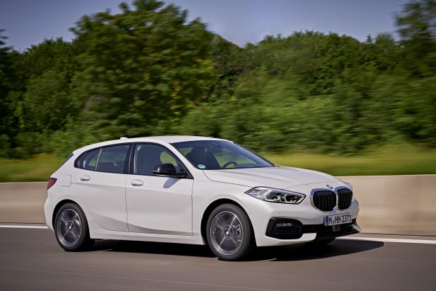 Ein weißer BMW 1er fährt auf einer Autobahn.