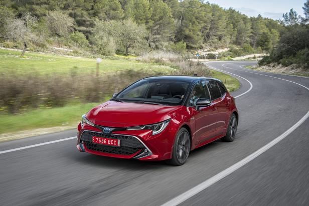 Ein roter Toyota Corolla fährt auf einer kurvenreichen Straße.