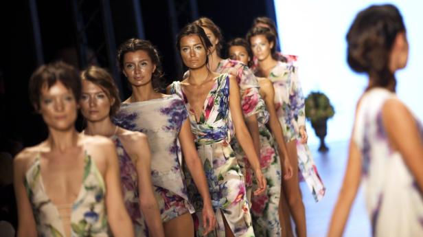 Models präsentieren florale Kleider auf einer Modenschau.