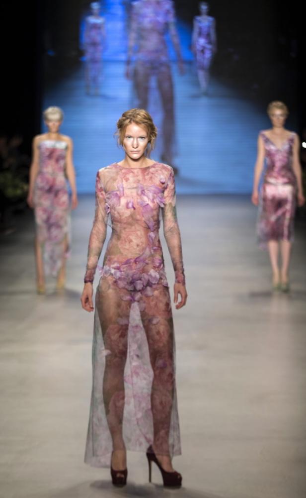 Eine Frau in einem transparenten, blumengemusterten Kleid auf einem Laufsteg.