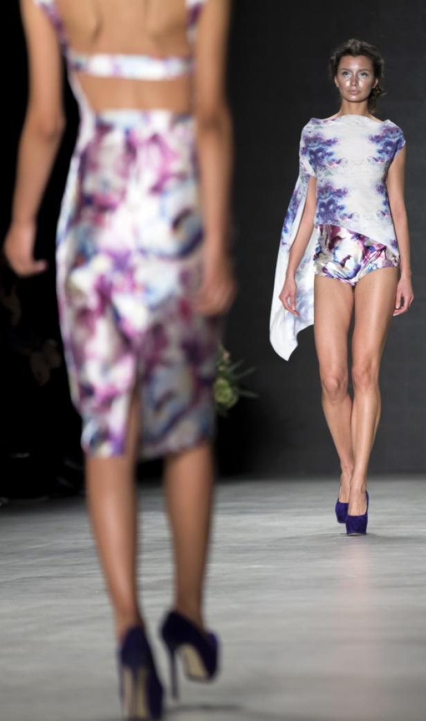 Zwei Models präsentieren farbenfrohe Mode auf einem Laufsteg.