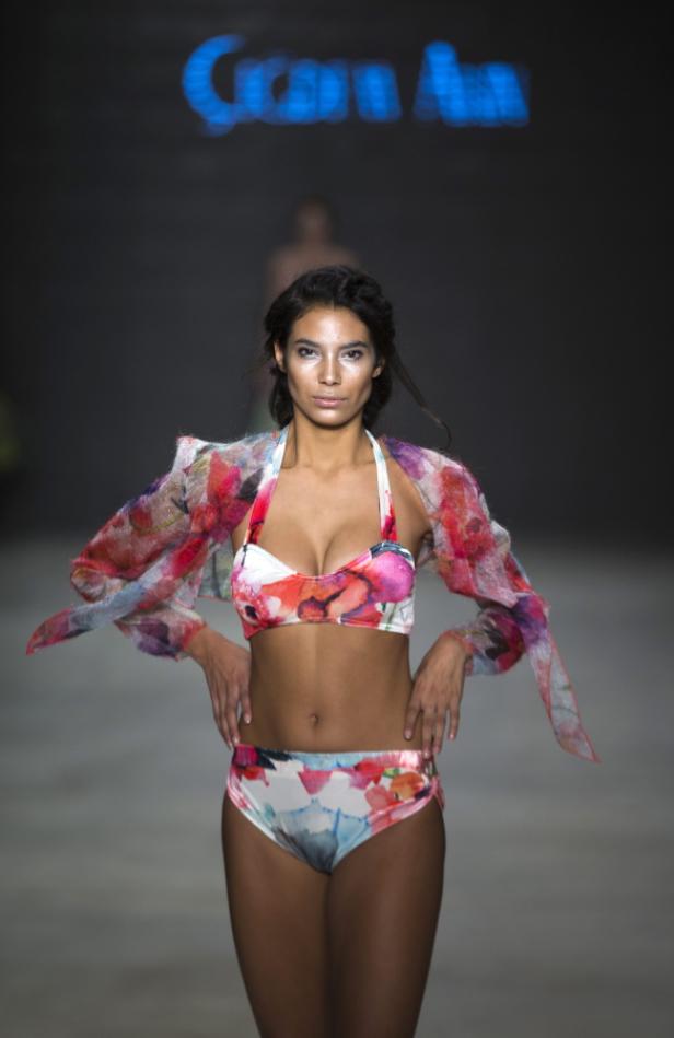 Eine Frau präsentiert ein buntes Bikini-Set mit Blumenmuster auf dem Laufsteg.