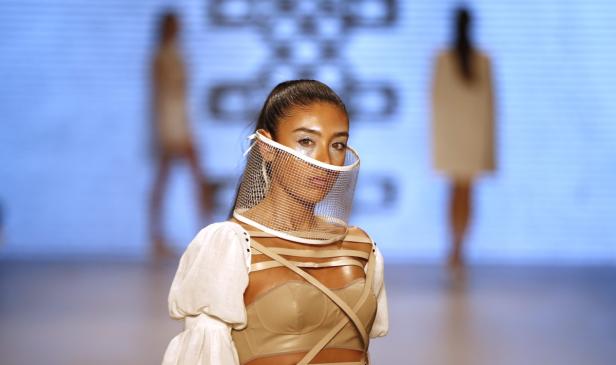 Eine Frau mit einem avantgardistischen Gesichtsschirm auf einem Laufsteg.