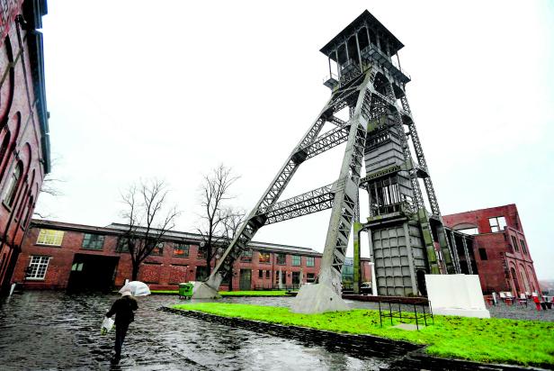 A woman holding an umbrella walks in a former coal mine in Genk