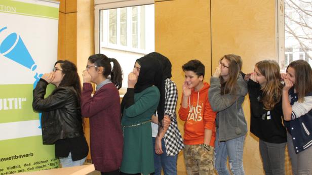 Eine Gruppe Jugendlicher flüstert sich gegenseitig etwas zu.