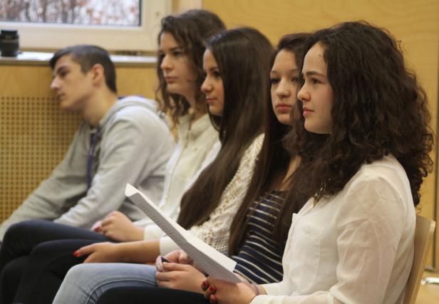 Eine Gruppe junger Leute sitzt aufmerksam in einer Reihe.