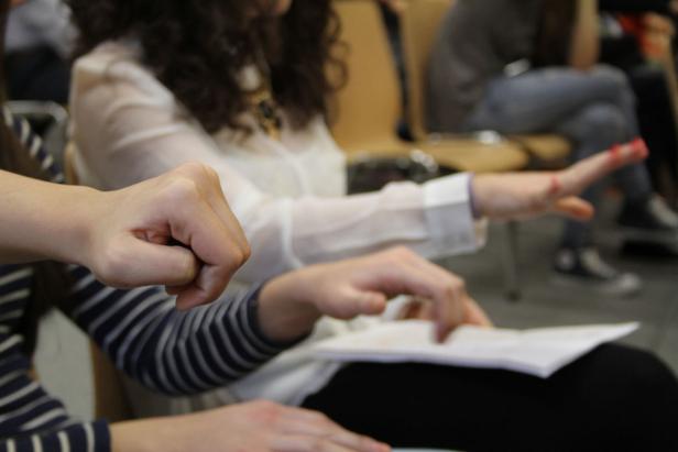 Eine Person ballt die Faust, während eine andere ein Blatt Papier berührt.