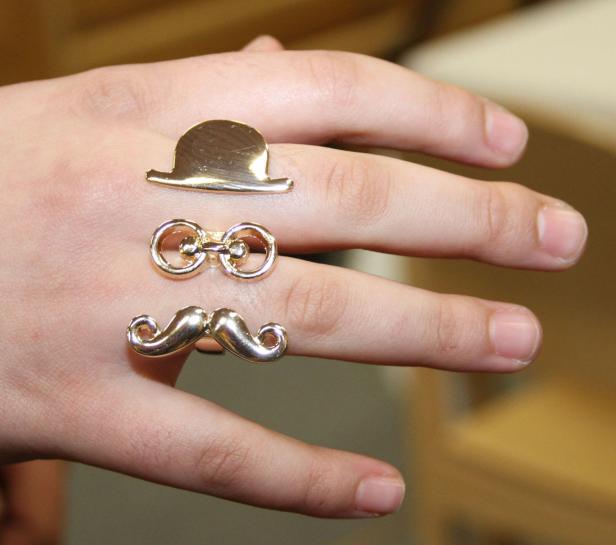 Eine Hand trägt Ringe in Form eines Huts, einer Brille und eines Schnurrbarts.