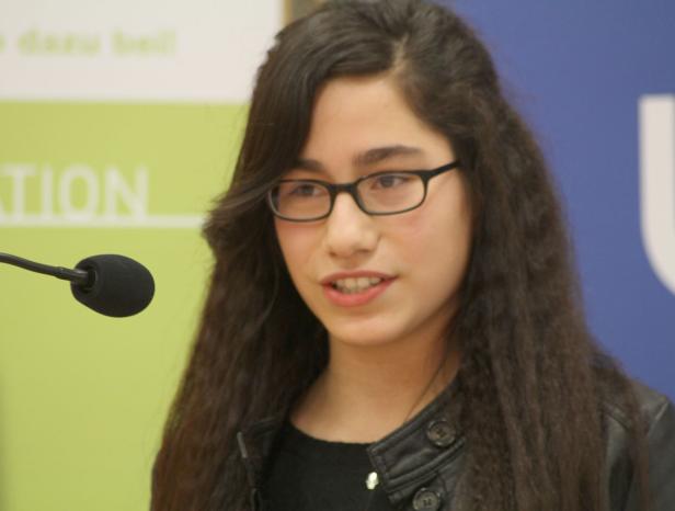 Eine junge Frau mit Brille spricht vor einem Mikrofon.