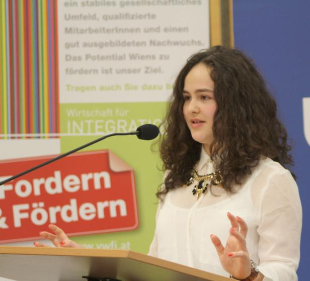 Eine junge Frau spricht bei einer Veranstaltung am Rednerpult.