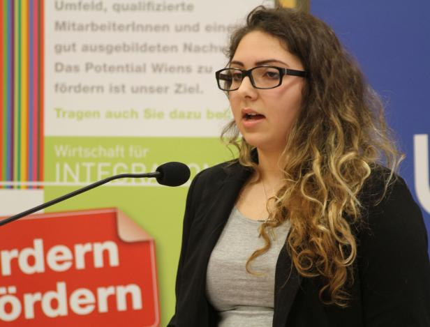 Eine Frau mit Brille spricht bei einer Veranstaltung am Mikrofon.