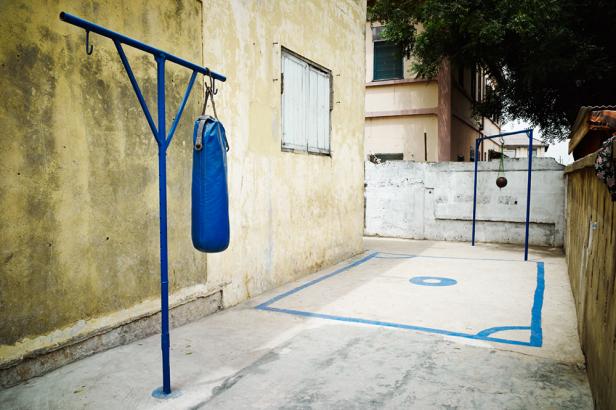 Ein blauer Boxsack hängt an einem Gestell auf einem Hof.
