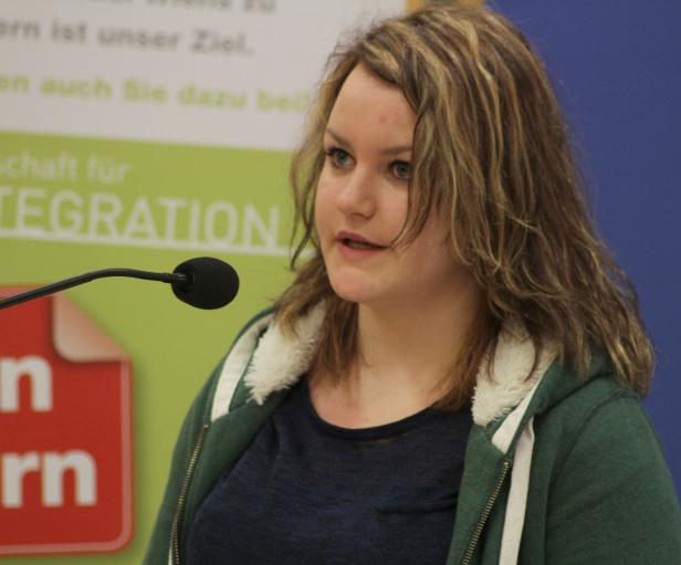 Eine Frau spricht bei einer Veranstaltung vor einem Mikrofon.