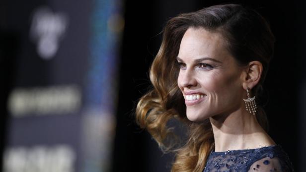 Nahaufnahme von Hilary Swank mit eleganten Ohrringen und gelocktem Haar.