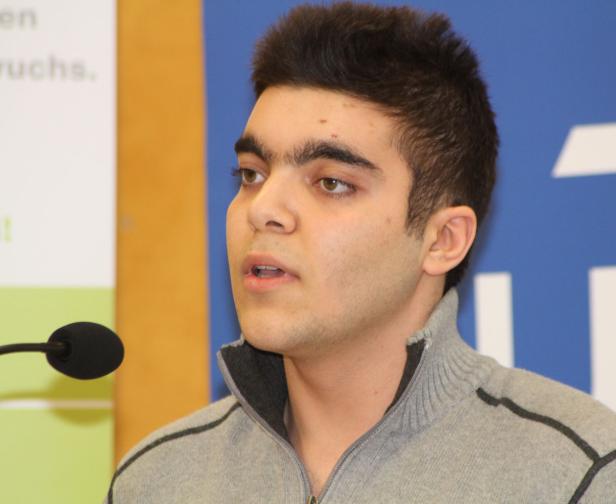 Ein junger Mann spricht an einem Mikrofon.