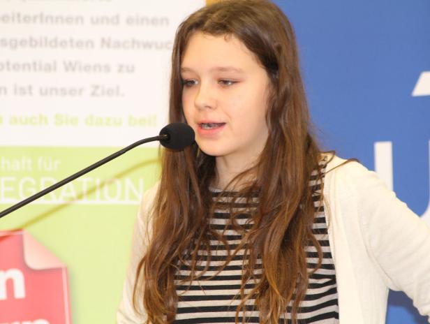 Ein junges Mädchen spricht bei einer Veranstaltung in ein Mikrofon.