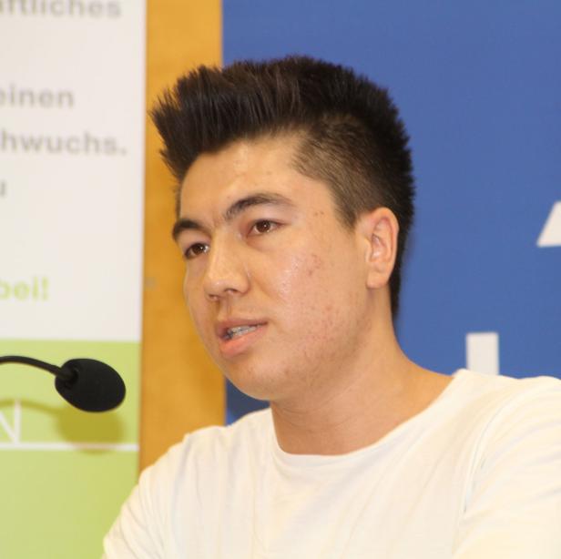 Ein junger Mann spricht an einem Mikrofon.