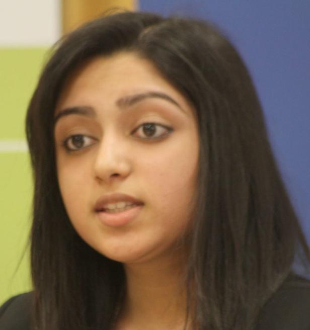 Eine junge Frau mit dunklen Haaren schaut zur Seite.