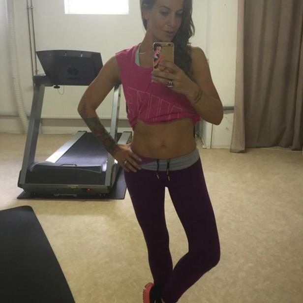 Eine Frau macht ein Selfie im Fitnessstudio, im Hintergrund ein Laufband.