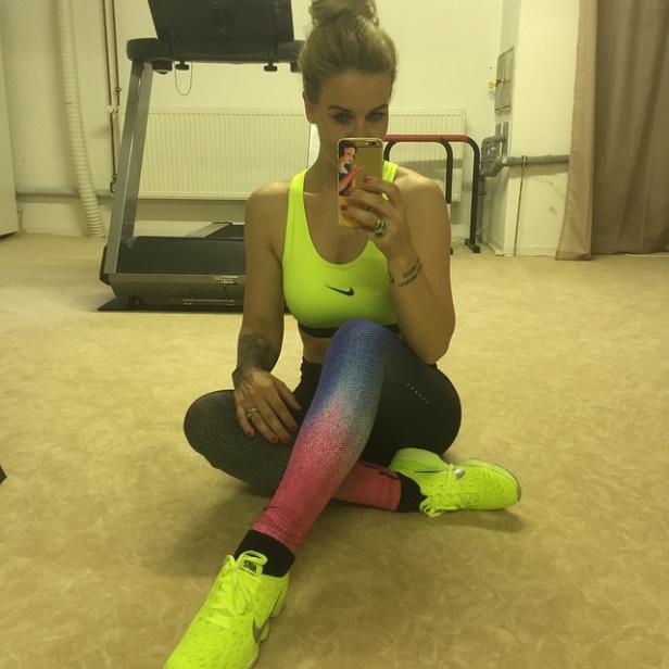 Eine Frau im Sportoutfit macht ein Selfie in einem Fitnessraum.