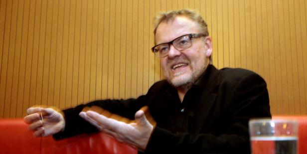 Ein Mann mit Brille gestikuliert während eines Gesprächs.