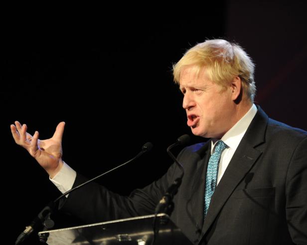 Boris Johnson hält eine Rede vor Mikrofonen.