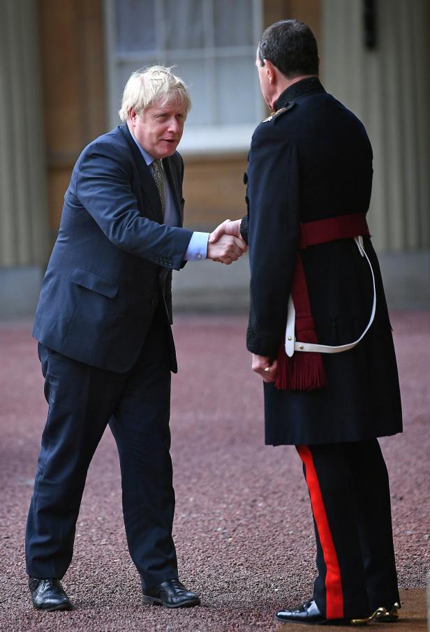 Boris Johnson schüttelt einem Mann in Militäruniform die Hand.