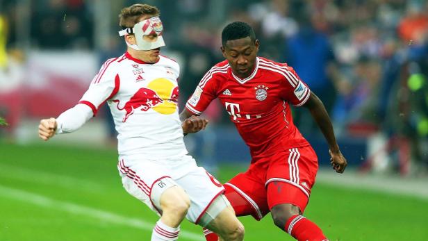 Zwei Fußballspieler im Zweikampf, einer mit einer Gesichtsmaske.