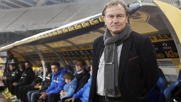 Ein Mann mit Schal steht vor einer Auswechselbank im Stadion.