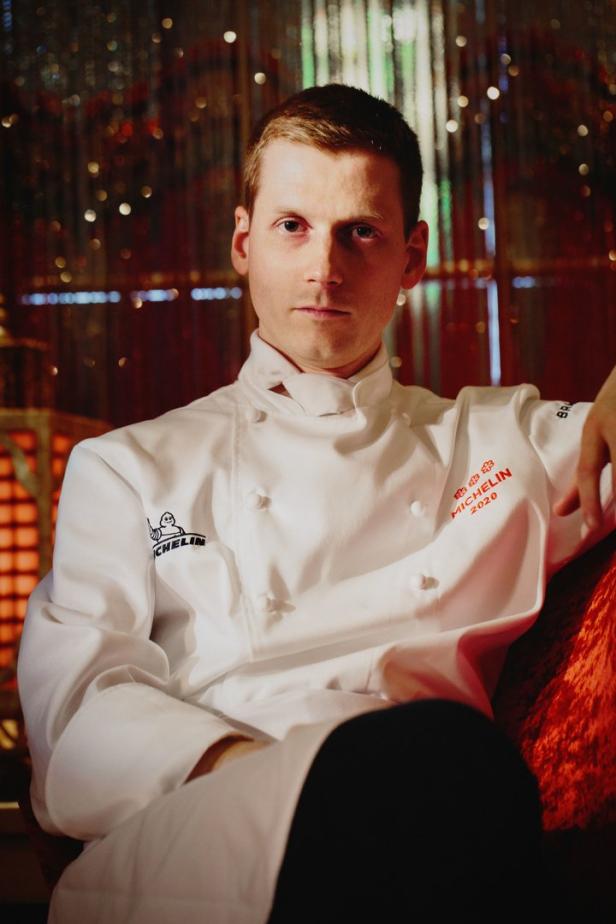 Ein Koch in seiner Kochuniform mit Michelin-Stern-Logo.