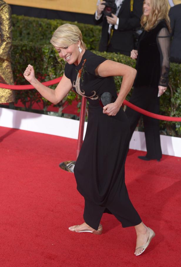 Eine Frau in einem schwarzen Kleid geht auf einem roten Teppich.